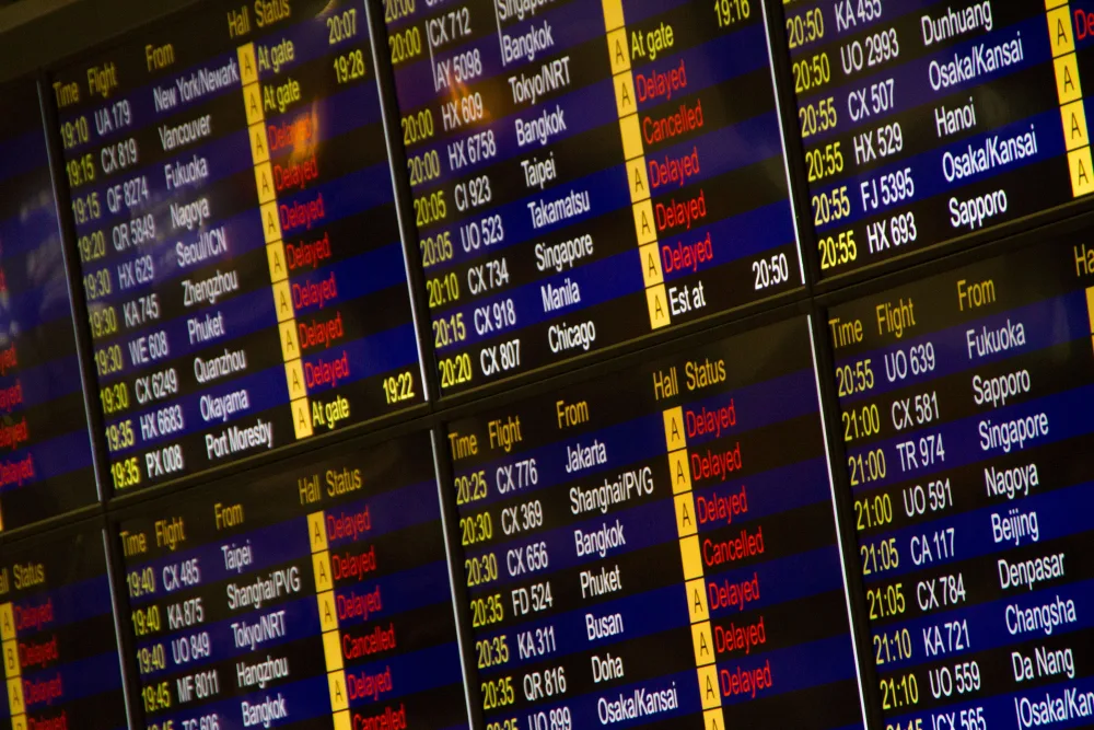 Travelers at an airport departure board after a flight cancellation