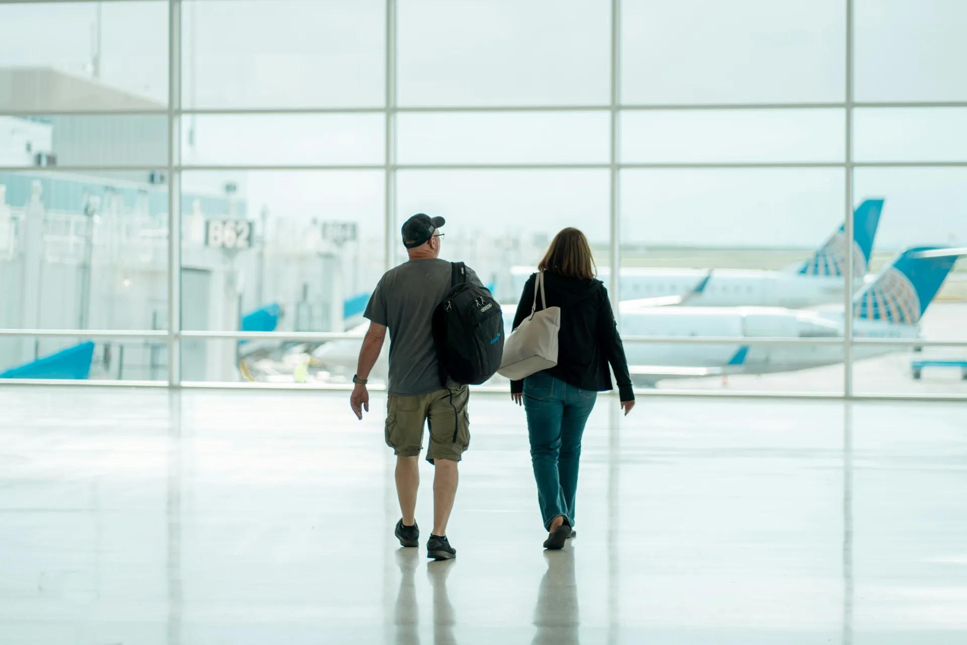 Two travelers walking together through a bright airport terminal toward their departure gate